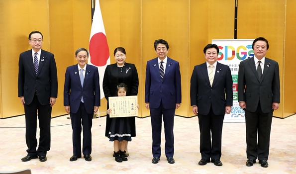 表彰式で安倍晋三首相と並ぶ、そらのまちほいくえんの古川理沙代表と園児代表